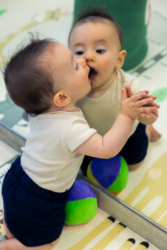 Baby playing with reflection, discovering self-awareness in mirror