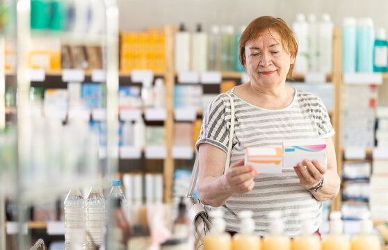 Ederly woman in summer clothes looking for medicine in a pharmacy