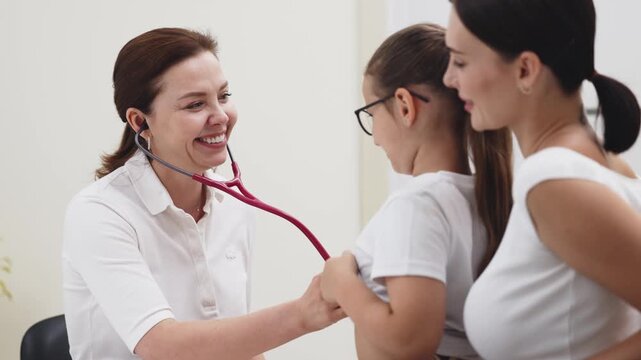Mother accompanying her daughter during a pediatric examination as the doctor uses a stethoscope. Concept child health, pediatric consultation, family healthcare, preventive care, medical examination.