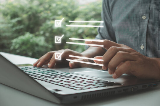 Businessman using laptop, online checklist survey, filling out digital exam, questionnaire and taking an assessment satisfaction with checkboxes. Business performance monitoring and evaluation concept