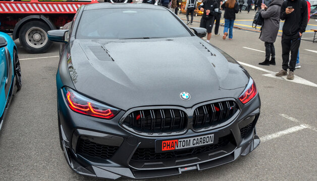 Sleek matte black BMW M8 Coupe featuring aggressive carbon fiber aero upgrades, red brake calipers, and custom red-accented headlights that emphasize its powerful stance