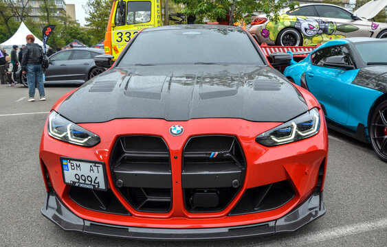 Red BMW M4 Coupe (G82 series) with an aggressive front fascia highlights the large black kidney grille, sleek LED headlights, and a carbon fiber hood