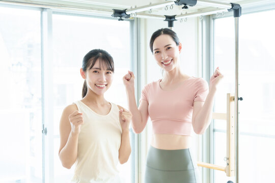 ピラティススタジオでガッツポーズをするインストラクターと生徒