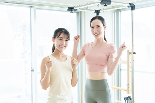 ピラティススタジオでガッツポーズをするインストラクターと生徒