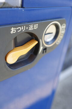 自動販売機の小銭投入口とお釣り返却レバー。ブルーの機体と金色ハンドル