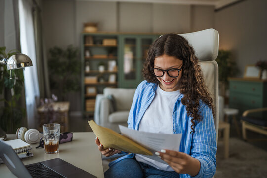 Young girl opening envelope with happy news at home