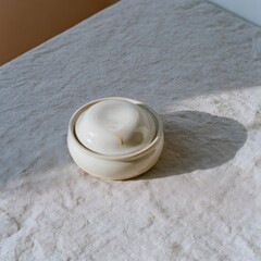 Fototapeta premium Hand-thrown stoneware butter dish with domed lid on linen surface