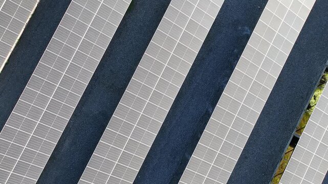 Aerial view of a solar panel and battery energy storage system. Clean, renewable solar energy. Located near a highway and cars, amidst an area of ​​greenery and farmland.