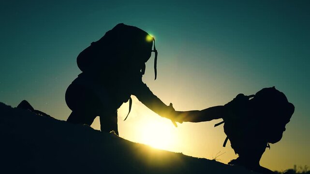 Business teamwork. Achieve your goal. Climbers holding hands, climb to top mountain. Silhouettes. Victory business team. Free people strive victory. Teamwork travel. Tourists conquer mountain together