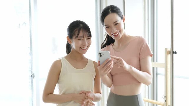 ピラティススタジオでスマートフォンを使う女性