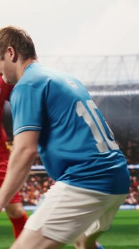 Vertical screen: Soccer players in red and blue jerseys dribbling for ball possession on pitch, match action and footwork for intense attack, opponents defending goal net, for football match content.