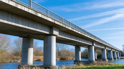 Obraz premium Concrete Viaduct Bridge Spanning a River with Blue Sky and Clouds