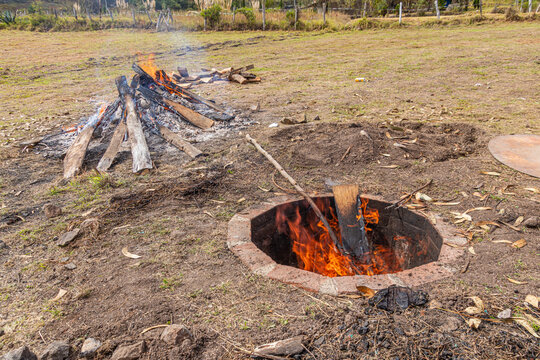 A traditional underground earth oven pit prepared for Pachamanca cooking in Ecuador. Heated volcanic rocks, and rustic earthen hole is ancestral culinary method practiced in the Andean highlands