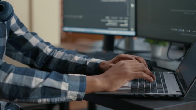 Developer hands type source code on a keyboard in front of computer screens, showing programming workflow, data entry and software production, during a technical debugging task.
