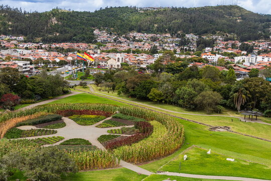 A beautiful cityscape of Cuenca, Azuay Province, Ecuador. A picturesque view of the city surrounded by green hills and mountains, as well as the church, traditional tile-roofed buildings, and the park