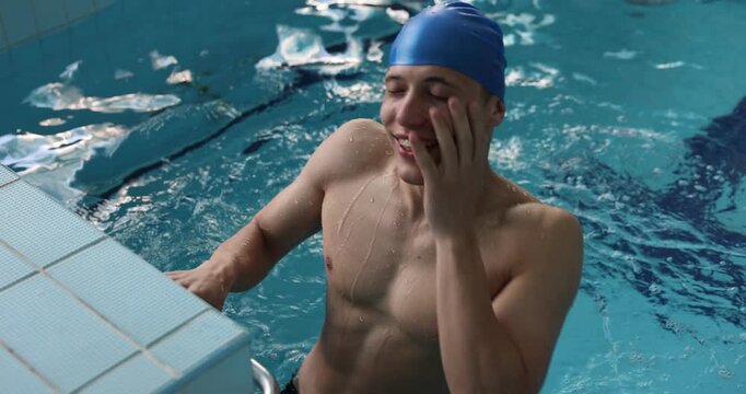 Athletic man in cap diving near starting block in swimming pool