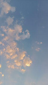 Vertical view of beautiful golden hour clouds on blue sky background at sunset or sunrise
