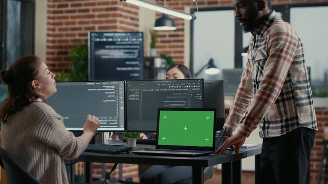 Software developer writes programming code beside a green screen chroma key mockup, creating replaceable display space for app interface work