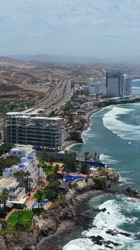 Vertical drone orbit over Las Rocas Resort near the Cristo del Sagrado Coraz&oacute;n monument in Rosarito, Baja California, Mexico