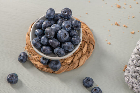 Fresh blueberries in a small white bowl on a woven placemat