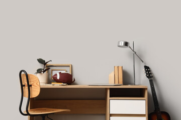 Fototapeta premium Modern wooden desk with a football, plant, and guitar in a minimalist room, home office or student study space