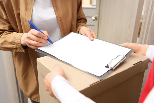 Customer signing delivery receipt for a cardboard box package from a courier, Home delivery service
