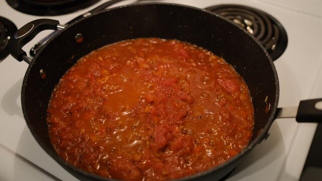 Po&ecirc;le contenant des poivrons et des oignons &eacute;minc&eacute;s, sur une cuisini&egrave;re. Pr&eacute;paration d'une chakchouka.