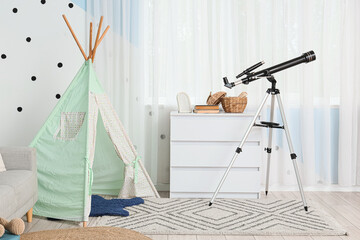 Interior of stylish childrens room with teepee, dresser and modern telescope near window © Pixel-Shot