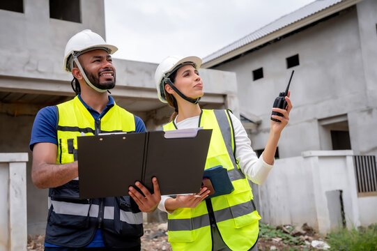 Civil construction site managers holding clipboard at residential construction site, inspection unfinished residential building during daytime, scene of house inspection and real estate development.