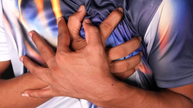 Young man suffering from severe chest pain clutching heart in pain during heart attack indoors