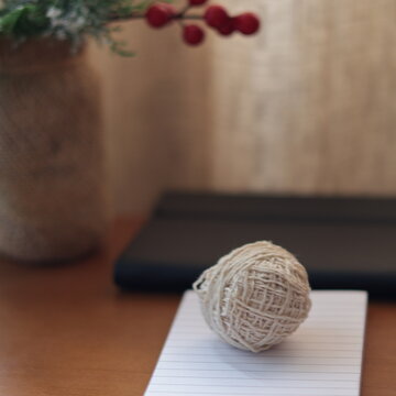 Una mesa de madera con un adorno de navidad una libreta de papel y varios objetos de escritorio 