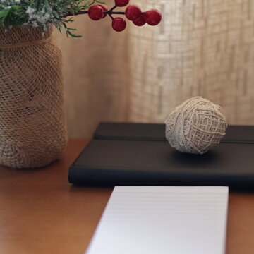 Una mesa de madera con un adorno de navidad una libreta de papel y varios objetos de escritorio 