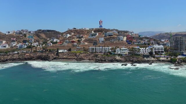 Christ of the Sacred Heart (Cristo del Sagrado Coraz&oacute;n) monument above Las Rocas Resort and Spa in Rosarito, Mexico. Pan left aerial shot