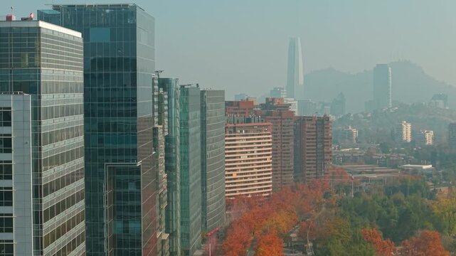 Aerial view dolly in of the modern glass buildings in Nueva Las Condes, with the Costanera Tower in the background, in Santiago, Chile