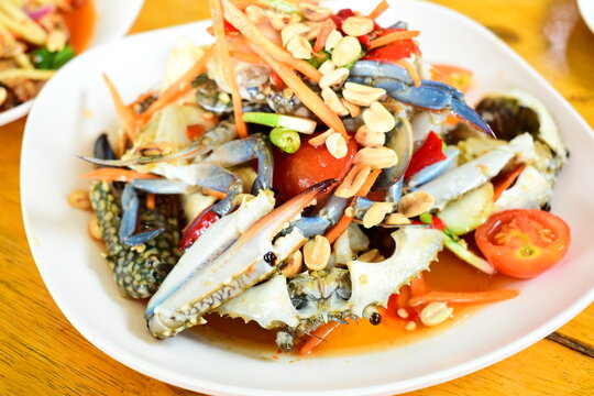 Thai spicy raw blue crab salad serve on a white plate, traditional Thai seafood cuisine