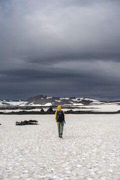 Hikers in snow-covered volcanic landscape with volcanic sand and petrified lava, crater of Askja volcano, Icelandic highlands, Iceland