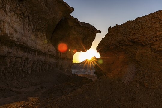 The morning sun shines through a striking rock formation in the Huqf stone desert, Arabian Peninsula, Sultanate of Oman