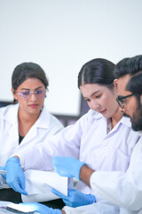 Fototapeta premium A laboratory analyst study DNA results on screen in a blue-lit research laboratory while wearing white lab coats and blue protective gloves and modern scientific innovation.