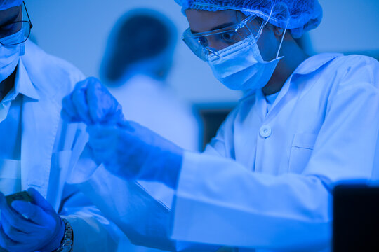 A laboratory analyst study DNA results on screen in a blue-lit research laboratory while wearing white lab coats and blue protective gloves and modern scientific innovation (No. 3818).