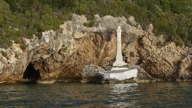 Monument to Count Santorre di Santarosa who died on May 8, 1825 in Navarino Bay defending the island of Sfaktiria, coast with stone monument next to a cave surrounded by green vegetation, morning light, islet of Tsichli Babas, island of Sfaktiria, Navarino Bay, Pylos, Peloponnese, Greece