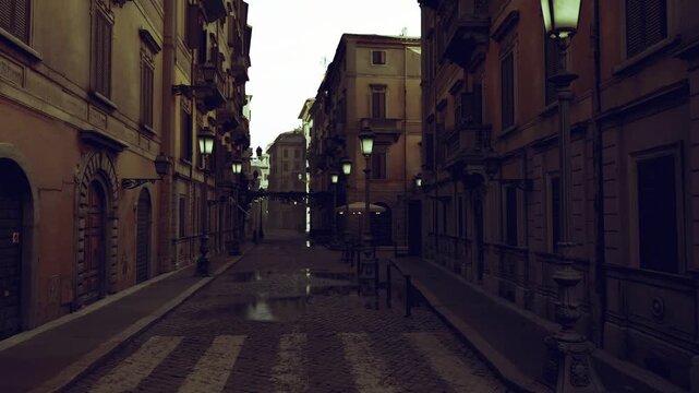puddled narrow street after storm, shimmering reflections of lamplight and facades, wet cobbles creating mirror texture, quiet urban corridor with evocative