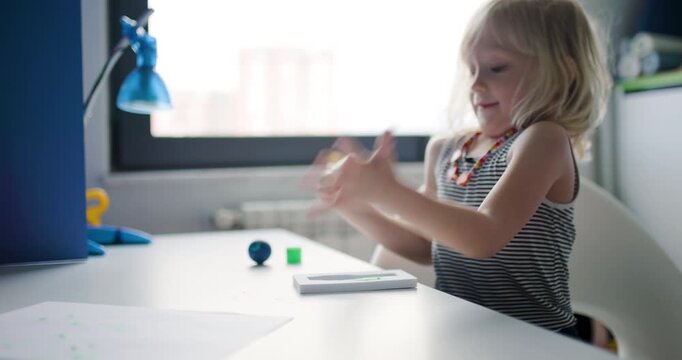 Little Blonde Girl Joyfully Drawing with Green Felt-Tip Pen at Her Desk in a Bright Sunny Room