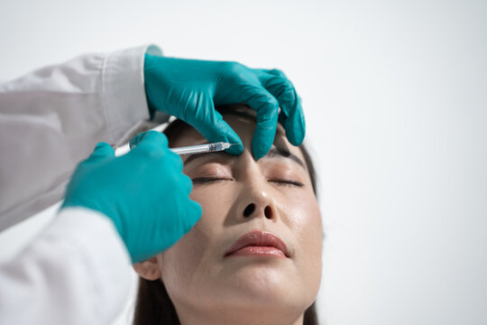 Close-up of a woman receiving a cosmetic forehead treatment from a doctor with gloved hands in a clinic.