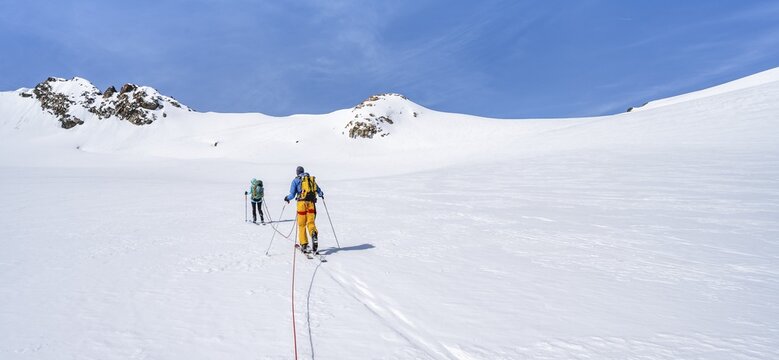 Ski tourers walking on the rope on the glacier, ascent on Berglasferner, behind summit Hinterer Wilder Turm, Stubai Alps, Tyrol, Austria