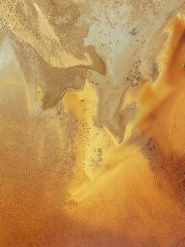 Abstract patterns in a pool in the mineral-rich area of the Rio Tinto mines. The colour is caused by oxidised iron minerals. Aerial view. Drone shot. Huelva province, Andalusia, Spain