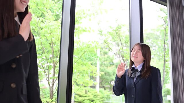 [スローモーション]学校で笑顔であいさつを交わす日本人女子中学生や高校生2人の下校や登校シーンと学校生活のイメージ　バイバイ～＆おはよ～！の動画