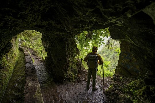 Hikers on a trail along a levada through a tunnel, Levada do Caldeir&atilde;o Verde, Parque Florestal das Queimadas, Madeira, Portugal