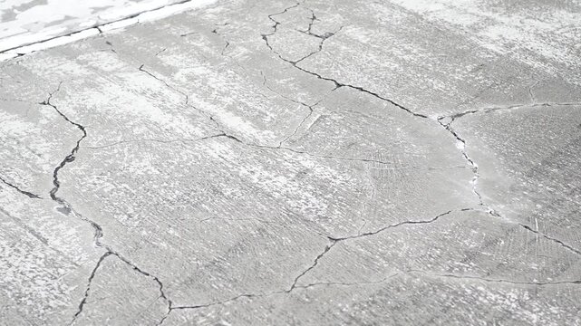 Close up cinematic shot of water flowing through cracks on a weathered concrete surface creating dynamic patterns