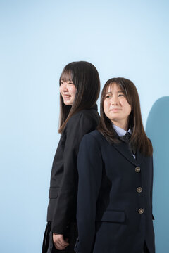 水色背景の未来を見つめて笑顔を見せる日本人女子高校生　2人で夢や進路を考える学校生活横顔のクローズアップ縦