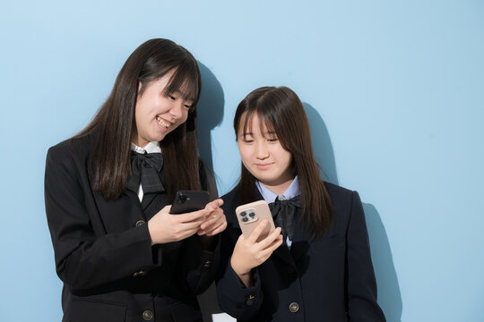 スマートフォン(スマホ)を見る日本人女子中学生、女子高校生　2人で情報を共有する学校生活とコミュニケーション、スマホの安全な使い方イメージ
